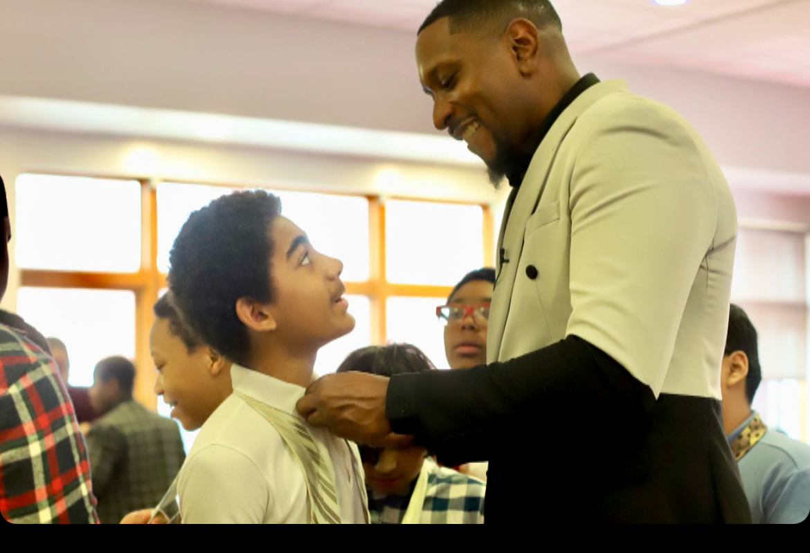 Michael Spence helping a young person with a tie